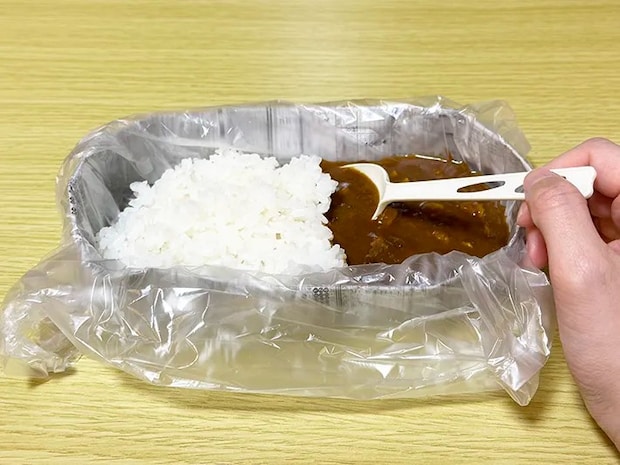 新聞紙で作った皿に『アイラップ』を被せ、その上にご飯とカレーのルーを入れた画像（撮影：grapeライフハック編集部）