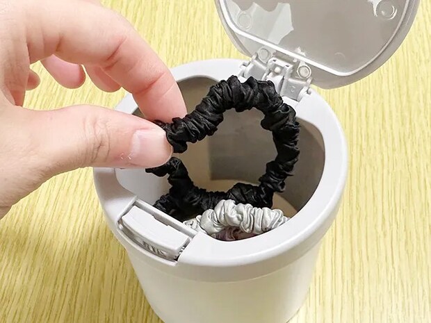 『ワンタッチ綿棒ケース』に髪ゴムを入れている画像（撮影：grapeライフハック編集部）