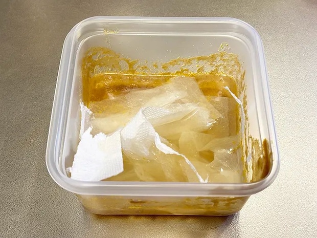 水と洗剤が入った汚れたプラ容器に、ちぎったキッチンペーパーを浮かべている画像（撮影：grapeライフハック編集部）