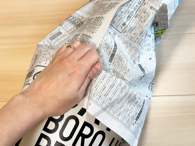 巻き終わりの部分を手で握り、新聞紙がずれないよう固定している画像（撮影：grapeライフハック編集部）