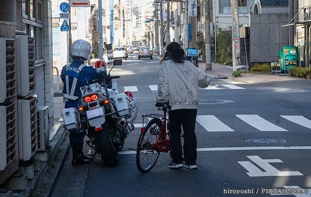警察官と話す自転車を降りた女性の写真