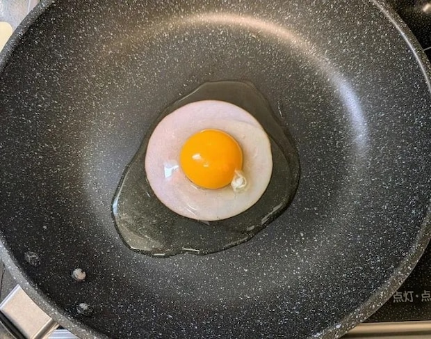 ハムの上に卵を割り入れる様子（撮影：grapeフード編集部）