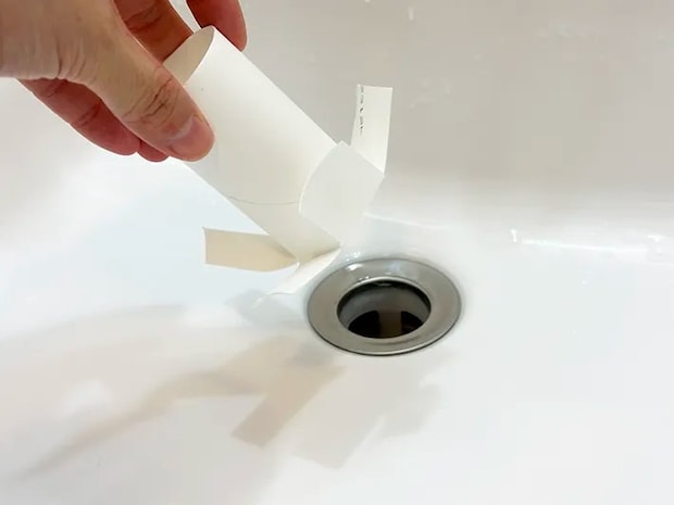 加工したトイレットペーパーの芯を排水口に入れようとしている画像（撮影：grapeライフハック編集部）