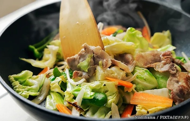 木製のキッチンツールでフライパンを使用する写真