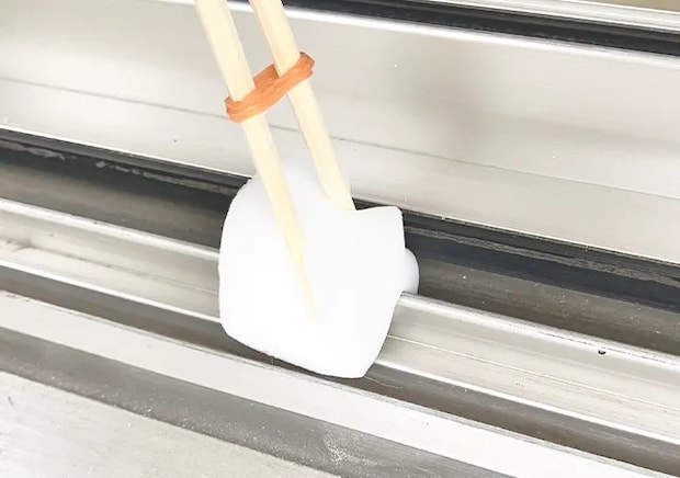 割り箸、輪ゴム、スポンジを合体させたアイテムで窓の枠掃除をする場面（撮影：grape編集部）