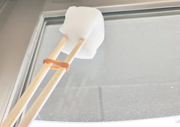 割り箸、輪ゴム、スポンジを合体させたアイテムで窓掃除をする場面（撮影：grape編集部）