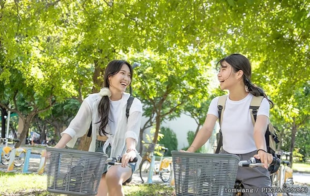 仲よく並んで自転車に乗る女性の写真