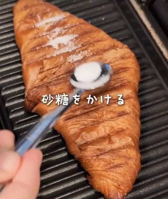 クロワッサンに砂糖を振りかけている様子