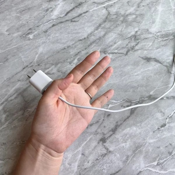 親指と人差し指で電源アダプターを挟んでいる様子（撮影：grapeライフハック編集部）