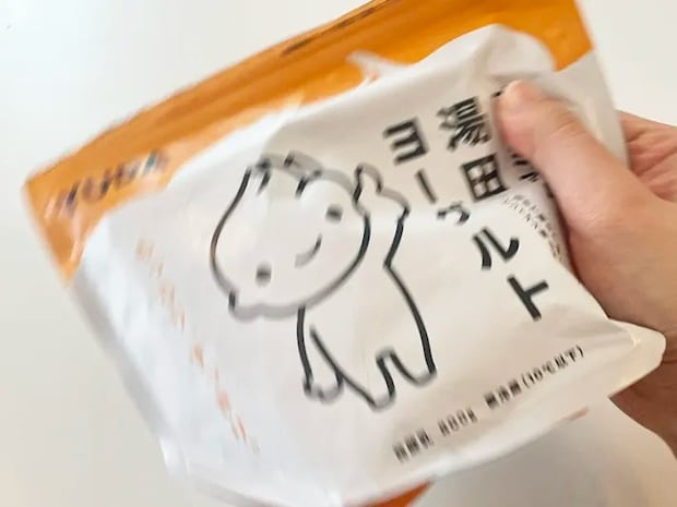 牛乳を入れたプレミアム湯田ヨーグルトを振る写真（撮影：grapeフード編集部）