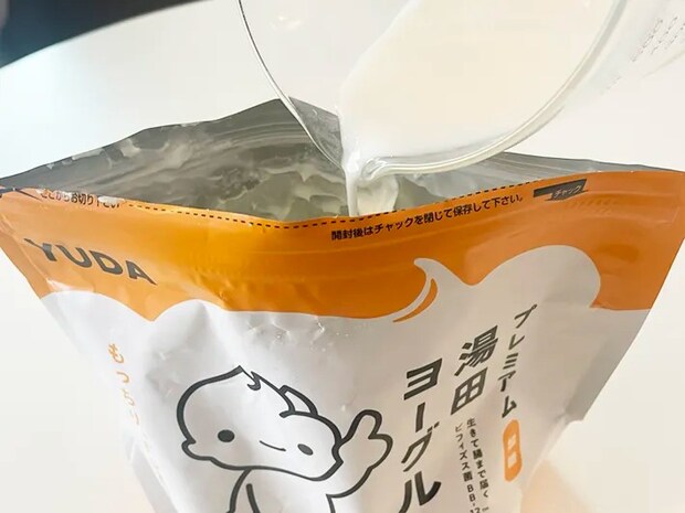 プレミアム湯田ヨーグルトに牛乳を入れる写真（撮影：grapeフード編集部）