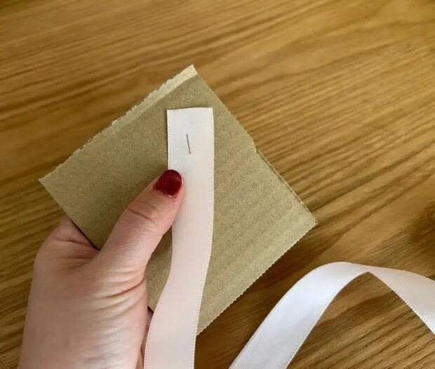 ダンボールのまち針にリボンを引っ掛けている様子（撮影：grapeライフハック編集部）