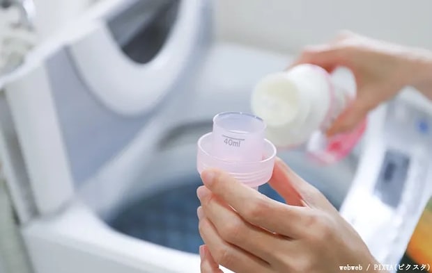洗濯機に柔軟剤を計って入れる写真