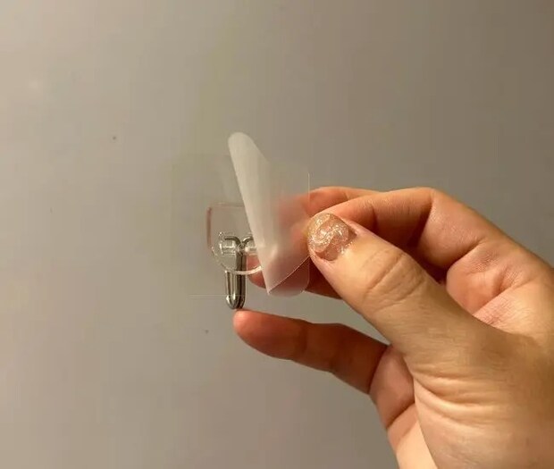 フックを冷蔵庫横に貼りつける様子（撮影：grapeライフハック編集部）