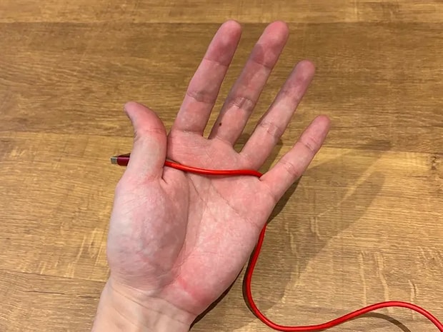 親指で挟んだ充電ケーブル（撮影：grapeライフハック編集部）