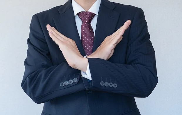 手で『ダメ』の意思表示をする男性の写真