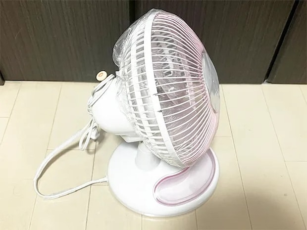 『セリア』のシャワーキャップを扇風機にかぶせる場面（撮影：grapeライフハック編集部）