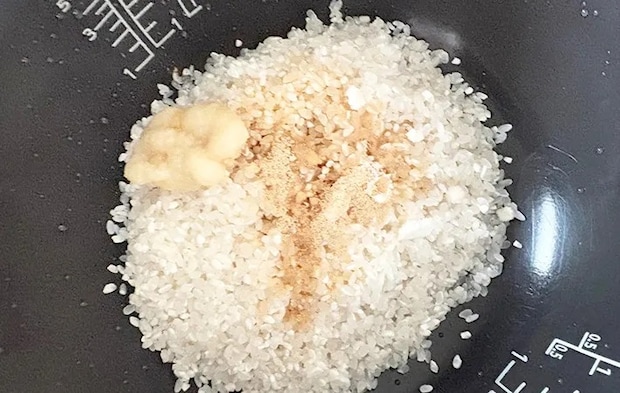 米、鶏ガラスープの素、醤油、にんにくチューブを炊飯釜に入れた画像（撮影：エニママ）