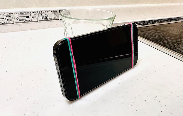 スマホに輪ゴムをかけてコップに立てかけている写真（撮影：grapeライフハック編集部）