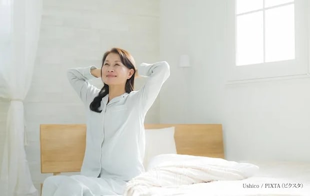 『ベッドでストレッチするシニア女性』の写真