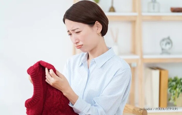 『衣替えで出したセーターに問題を見つけた女性』の写真