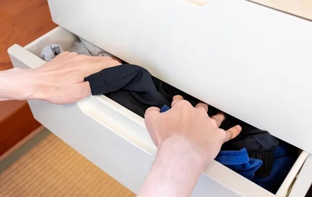 『服をドレッサーの引き出しに押し込む』写真