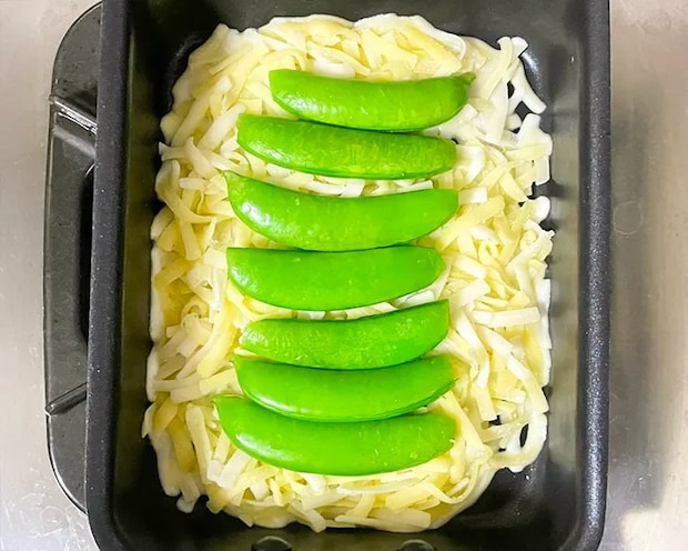 玉子焼き器にシュレッドチーズとスナップエンドウを重ねる写真（撮影：grapeフード編集部）