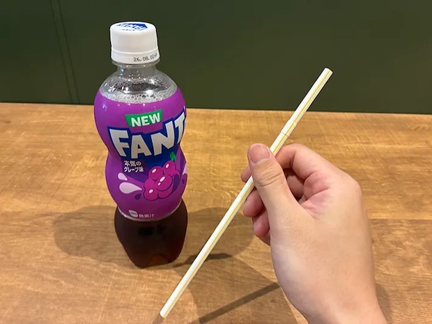 机に置かれたペットボトル飲料と、指でつかんだストロー（撮影：grapeライフハック編集部）
