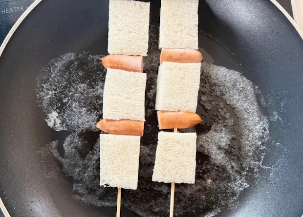 フライパンに竹串に食パンとウインナーを刺したものを並べた画像（撮影：エニママ）