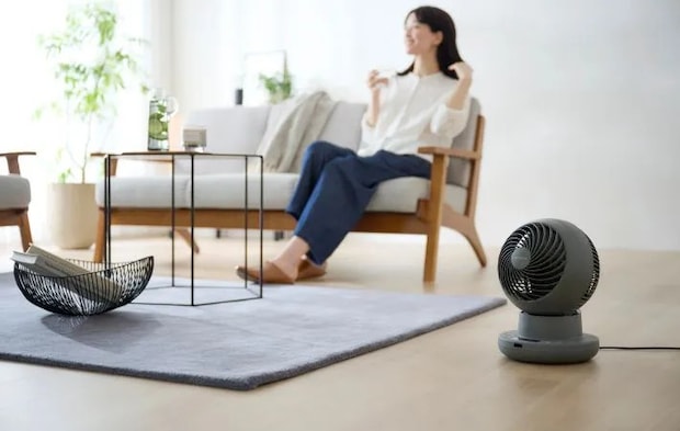 ソファに座る女性とサーキュレーターの写真