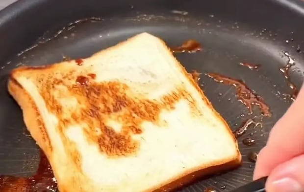 パンを照り焼きソースにつけている画像