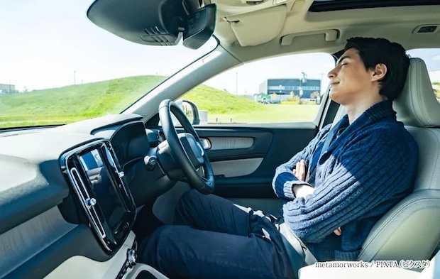 『自動車の運転席で眠る男性ドライバー』の写真