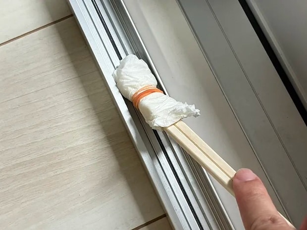 キッチンペーパーをつけた割り箸でサッシを掃除する場面（撮影：grapeライフハック編集部）