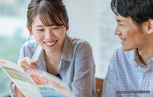 『旅行のパンフレットを見ながら計画を立てる男女』の写真