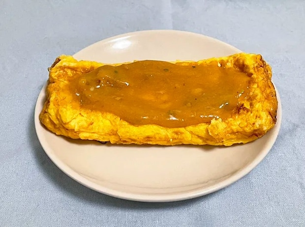 『うどんスープマヨ』を玉子焼きにかける写真（撮影：grapeフード編集部）