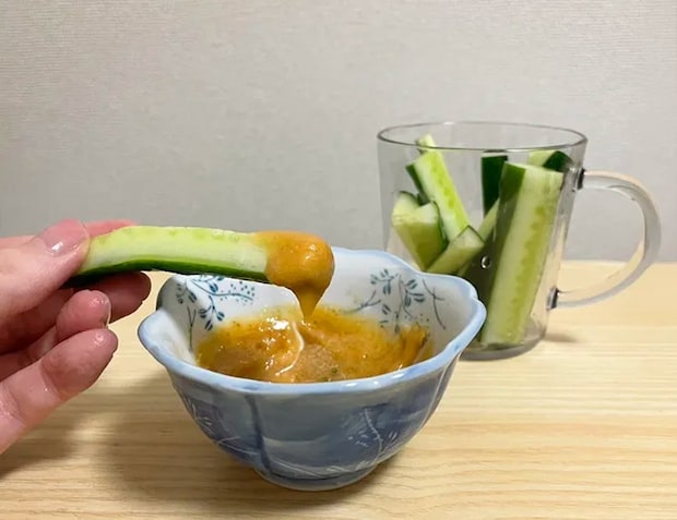 キュウリを『うどんスープマヨ』につけて食べる写真（撮影：grapeフード編集部）