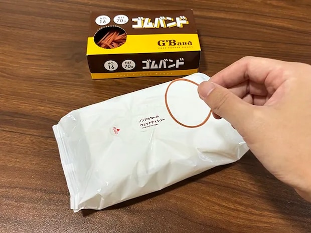 机に置かれたウェットシートと、指でつかんだ輪ゴム（撮影：grapeライフハック編集部）