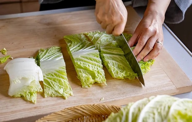 木製のまな板で白菜を切っている写真