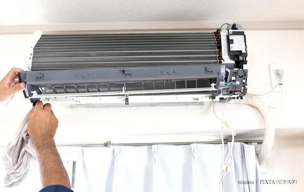 『住宅のエアコン点検をする作業員の手元』の写真