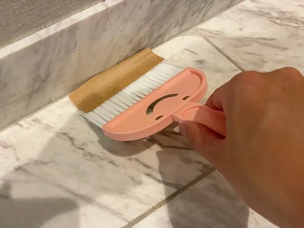 ガムテープをつけたミニほうきで玄関を掃除する場面（撮影：grapeライフハック編集部）