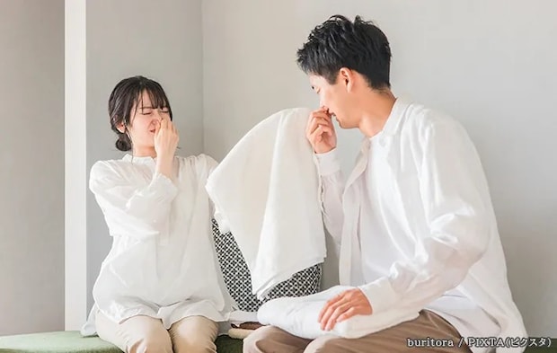 臭うタオルと鼻をつまむ人の写真