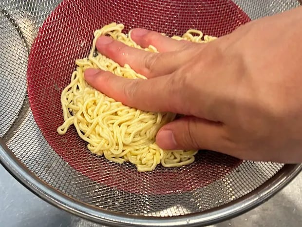 ゆでた麺を押して水切りする場面（撮影：grapeフード編集部）
