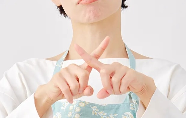 手でバツを作る女性