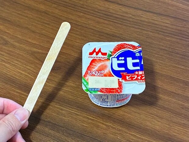 机に置かれたヨーグルトと、手で持ったアイスの棒（撮影：grapeフード編集部）