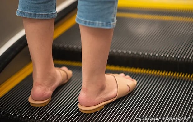 サンダルでエスカレーターに乗る人の写真