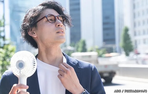 ハンディファンで涼む男性の写真