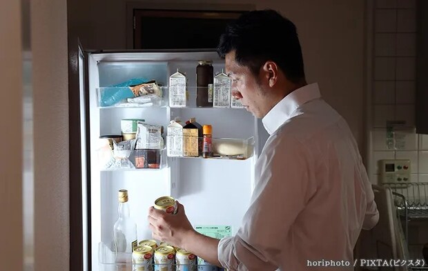 冷蔵庫から缶ビールを取り出す男性の写真