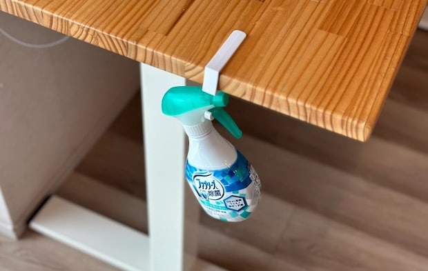 『吊り戸棚用フック』をデスクに設置し消臭・除菌剤をひっかけている写真（撮影：grapeライフハック編集部）