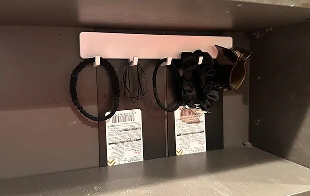 洗面台の棚に差し込んだブックエンドにマグネット対応の便利グッズを貼りつけて小物の整理している写真（撮影：grapeライフハック編集部）