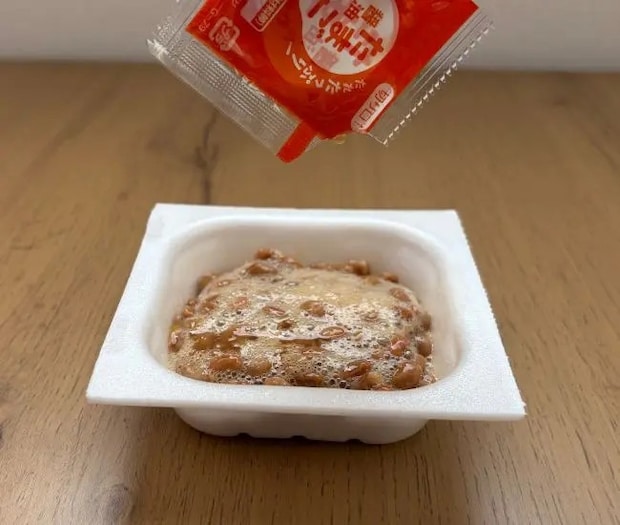 付属のタレを加える（撮影：grapeフード編集部）